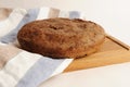 Fresh homemade round malted rye bread on wooden board. White background, linen fabric Royalty Free Stock Photo