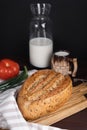 Fresh homemade rye bread, tomato, bunch onion, clay mug and bottle of milk on wooden cutting board Royalty Free Stock Photo