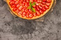 Fresh homemade strawberry shortcrust tart pie stuffed with custard vanilla cream . Sliced berries and mint leaf on the trendy dark Royalty Free Stock Photo