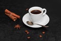 Fresh hot black coffee in white cup, coffee beans, cinnamon sticks, anise star on black background. Coffee time concept Royalty Free Stock Photo