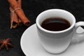 Fresh hot black coffee in white cup, coffee beans, cinnamon sticks, anise star on black background. Coffee time concept Royalty Free Stock Photo