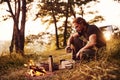 Fresh and hot drink. Man in black shirt near the campfire in the forest at his weekend time