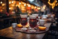 Fresh hot mulled wine a wooden table on Christmas market. Decorated and illuminated outdoor tables of a restaurant of cafe. Snowy