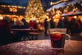 Fresh hot mulled wine a wooden table on Christmas market. Decorated and illuminated outdoor tables of a restaurant of cafe. Snowy