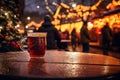 Fresh hot mulled wine a wooden table on Christmas market. Decorated and illuminated outdoor tables of a restaurant of cafe. Snowy