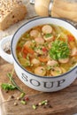 Fresh hot soup with meat sausage slices, beans, carrot, pasta and green herbs in bowl on wooden board Royalty Free Stock Photo