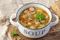 Fresh hot soup with meat sausage slices, beans, carrot, pasta and green herbs in bowl on wooden board Royalty Free Stock Photo