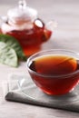 Fresh hot tea in glass cup, teapot and leaves on white wooden table Royalty Free Stock Photo