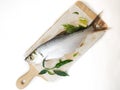 Fresh Indo-Pacific tarpon fish decorated with herbs and vegetables on a wooden pad,Selective focus.White background Royalty Free Stock Photo