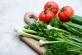 Fresh ingredients of salad on cutting board. Top view organic vegetables red tomatoes, cucumbers, bunch of parsley and green onion