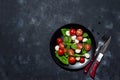 Fresh italian caprese salad with mozzarella and tomatoes on black plate over dark stone background with copy space, flat Royalty Free Stock Photo