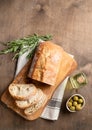 Fresh italian ciabatta bread cut  slices with rosemary and olive oil on wooden background. Top view  and copy space Royalty Free Stock Photo
