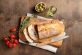 Fresh italian ciabatta bread cut  slices with tomato, rosemary and olive oil on wooden background. Top view  and copy space Royalty Free Stock Photo