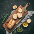 Fresh Italian ciabatta bread with olive oil, olives and rosemary on a black stone background. Top view, flat lay. Square toned Royalty Free Stock Photo