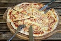 Fresh italian pizza Margherita pizza on wooden chopping board with fork and knife for two, top view Royalty Free Stock Photo