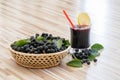 Fresh juice of chokeberry or Aronia melanocarpa with ice and lemon in glass and berry in baske Royalty Free Stock Photo