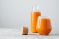 Fresh juice made of carrot filled in bottle and glass, cork near, isolated on white background, empty space. Detox drink. Healthy