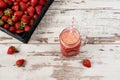 Fresh juice, shake, milkshake of strawberries in a mason jar with a straw. Pile of juicy ripe organic fresh strawberries in a bla Royalty Free Stock Photo