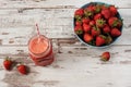 Fresh juice, shake, milkshake of strawberries in a mason jar with a straw. Pile of juicy ripe organic fresh strawberries in a Royalty Free Stock Photo