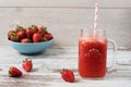 Fresh juice, shake, milkshake of strawberries in a mason jar with a straw. Pile of juicy ripe organic fresh strawberries in a Royalty Free Stock Photo