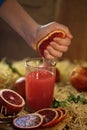 Fresh juice. Tarocco Red Orange Juice. Female hand squeezes juice from an orange into a glass