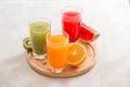 Fresh juices smoothie three glass red green orange tropical fruits water melon, kiwi, orange. Selective focus Royalty Free Stock Photo