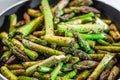 Fresh juicy asparagus sliced into pieces seasoned and salted lies in a pan