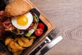 Fresh juicy bacon burger and fries on wooden table. Space for text Royalty Free Stock Photo