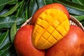 Fresh juicy beautiful diced mango fruit in bamboo basket on green leaves background, top view, close up, macro, copy space. Royalty Free Stock Photo