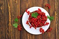 Fresh juicy berries of red currant in a white bowl on a brown wooden background. Harvest red currants