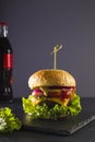 Fresh juicy burger on a black background. Delicious fast food. Vertical position. Copy space