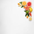 Fresh juicy citrus fruits with green leaves on light background, flat lay. Space for text Royalty Free Stock Photo