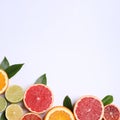 Fresh juicy citrus fruits with green leaves on white background, flat lay. Space for text Royalty Free Stock Photo