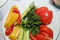 Fresh juicy fragrant cucumbers, tomatoes and bell peppers on a white plate