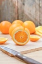 Fresh and juicy half and slice of orange fruit on a chopping block on weathered wooden table background. Royalty Free Stock Photo