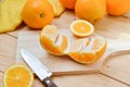 Fresh and juicy half and slice of orange fruit on a chopping block on weathered wooden table background. Royalty Free Stock Photo