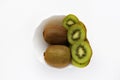 Fresh and juicy kiwi fruit, chopped and whole on a white plate. Delicious fruits and pieces of green kiwi