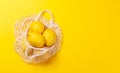 Fresh juicy lemons in a mesh bag, flat lay style Royalty Free Stock Photo