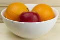 Fresh juicy natural apples and oranges in a shiny white plate on wooden background