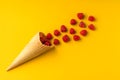 Fresh juicy natural raspberries fly out of the ice cream waffle cone. Minimalism on a yellow bright background. Healthy food and Royalty Free Stock Photo