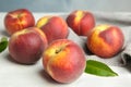 Fresh juicy peaches, leaves and fabric on wooden table Royalty Free Stock Photo