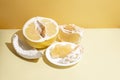 Fresh juicy pomelo half, wedges, pulp, and rind on a yellow background in sunlight