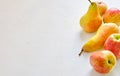 Fresh and juicy red apples and yellow pears on a white table