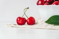 Fresh juicy red cherries in a white plate on the white wooden background. Copy, empty space for text