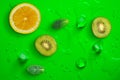 Fresh juicy slices of lemon, kiwi fruit and mint leaves on bright green background covered with water drops Royalty Free Stock Photo