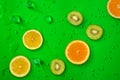 Fresh juicy slices of lemon, kiwi fruit and orange on bright green background Royalty Free Stock Photo