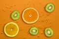 Fresh juicy slices of orange, kiwi fruit and lemon on bright orange background covered with water drops Royalty Free Stock Photo