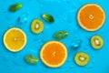 Fresh juicy slices of orange, kiwi fruit, lemon and mint leaves on bright blue background covered with water drops Royalty Free Stock Photo