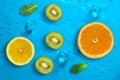 Fresh juicy slices of orange, kiwi fruit, lemon and mint leaves on bright blue background Royalty Free Stock Photo