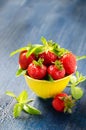 Fresh juicy strawberries and mint in a yellow mug on a blue wooden background Royalty Free Stock Photo